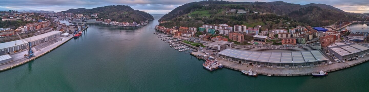 Pasai Donibane, Spain - 10 March 2026: Aerial view of the harbor, where the dark water meets the city's edge, contrasting with the lush green hills in the background.
