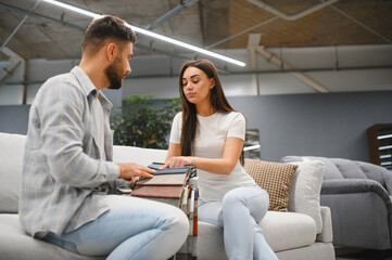 Fototapeta premium Couple choosing fabric samples for new sofa at furniture store
