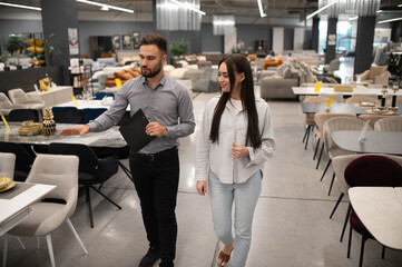 Sales consultant assisting woman choosing furniture in store