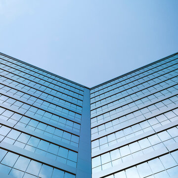Modern glass office building facade in urban area with blue sky