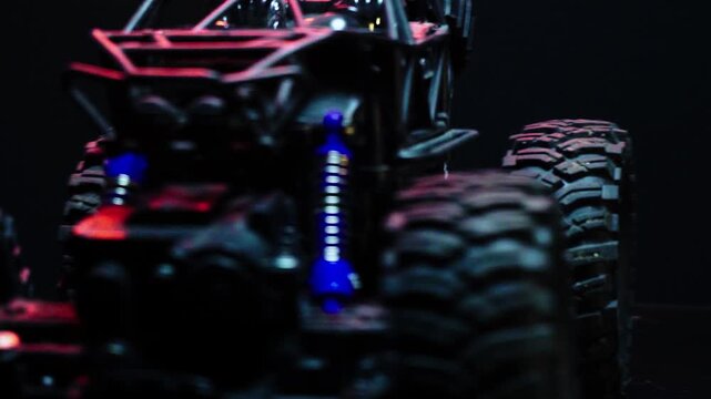 off-road toy cars turn with big tires art creative in water splashes 360 degree rotation on dark background with red backlight