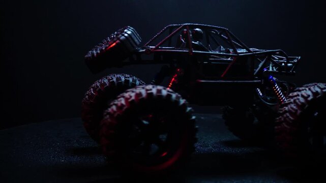off-road toy cars turn with big tires art creative in water splashes 360 degree rotation on dark background with red backlight
