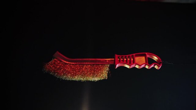 new metal brush with red handle, 360 degree rotation on a dark background with red backlight