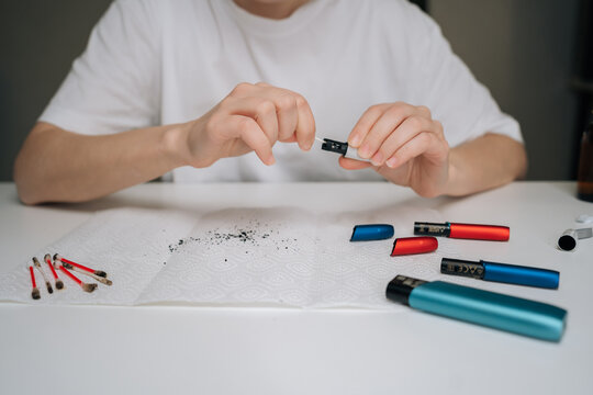 Person hands performing maintenance service on heated tobacco device, cleaning electronic cigarette with cotton swab and keeping vape device in proper condition, close-up cropped shot