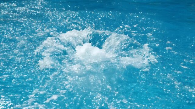 Intense splash of blue water erupts from pool surface, creating foam