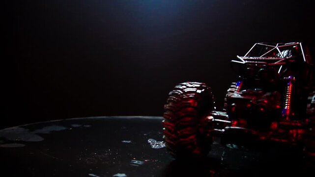 off-road toy cars turn with big tires art creative in water splashes 360 degree rotation on dark background with red backlight