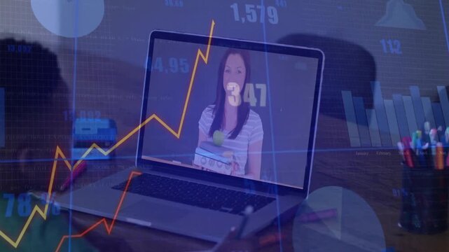 Schoolboy writing at desk while laptop showing teacher and animated graphs guiding remote education