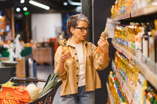 Adult woman comparing cooking oil products in supermarket