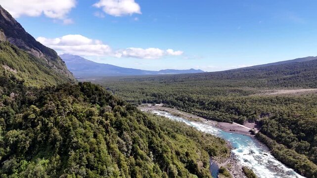Aerial moves forward along the turquoise Petrohu&eacute; River, revealing the iconic snow-capped cone of the Osorno Volcano in Vicente P&eacute;rez Rosales National Park, Chile