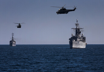 A group of patrol warships accompanied by a helicopter are carrying out a peacekeeping mission in the mediterranean sea. Battleships in action.  © ValStock
