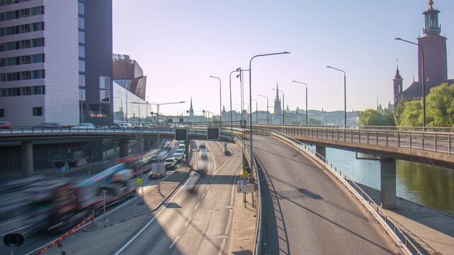 A high angle time lapse of a busy multilane highway next to a river on a clear day with the city hall in the background