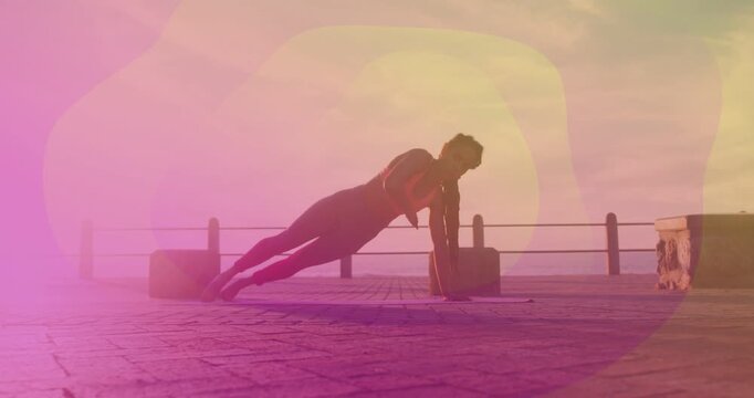 Woman holding high plank, shifting into side plank on mat with lens flare, fitness-toning core