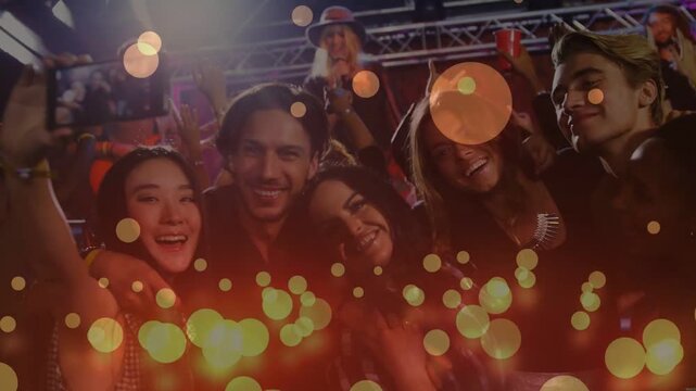 Friends huddling for selfie at music venue, lifting phone, capturing moment and creating soft bokeh