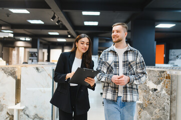 Sales assistant helping customer choosing new tiles