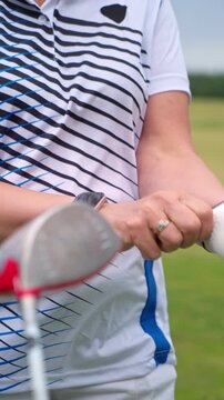 Close-up of a senior woman putting on a golf glove while wearing a smartwatch. High-tech sports integration, authentic active aging, and healthy lifestyle concept on a green course.