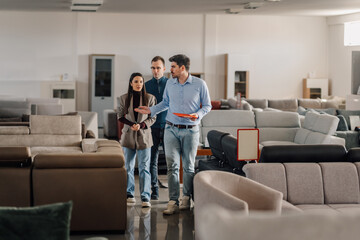 Naklejka premium Salesman advising couple in furniture showroom