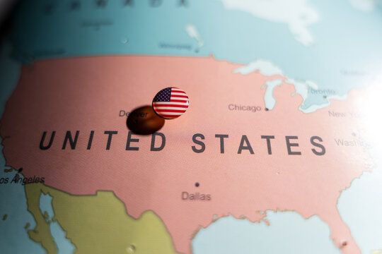 United States flag pin placed on a world map over North America, representing national identity, domestic travel, and American government policy
