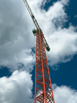 View of a towering red crane piercing the bright blue sky dotted with fluffy white clouds, standing tall in Sariyer, Istanbul, Turkey.