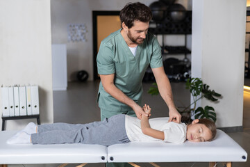 Obraz premium Specialist assisting girl with back rehabilitation exercises