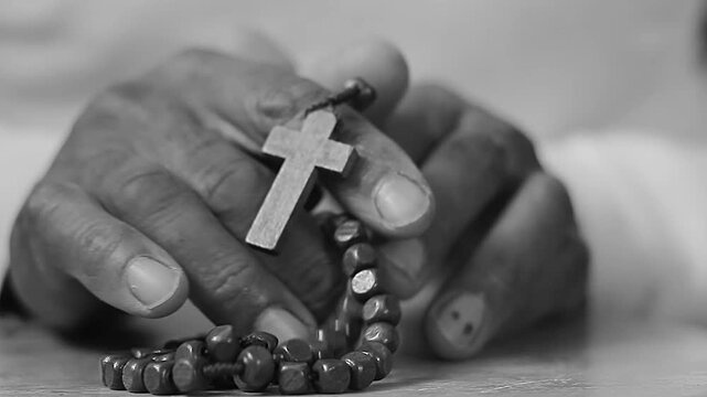 praying to God with hand's together with cross on table with people and black background stock video stock footage