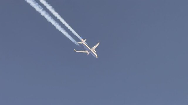Aerial cockpit view of the botton of a jet airplane and a fading contrail flying in a deep blue sky. Scene captured from a jet cokpit flying bellow.