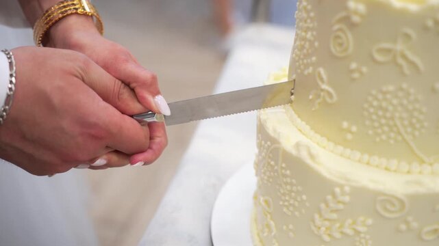 female and male hands cutting a wedding cake