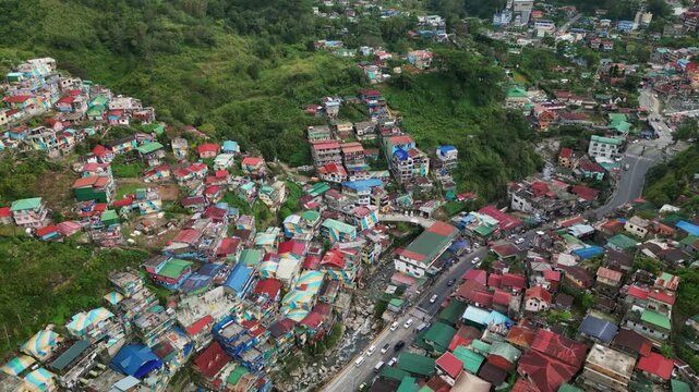 Scenic aerial overview of vibrant, urban settlement along hillside and busy highway - Valley of Colors, Benguet, Philippines