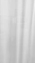 Obraz premium A soft blurred white sheer curtain hanging in bedroom creating bright airy and minimalist atmosphere with gentle vertical folds and natural light filtering through the fabric