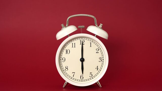 A crisp white alarm clock, a beacon of punctuality, sits poised against a striking scarlet canvas. Its hands are perfectly aligned at six o'clock, marking a profound moment of readiness.