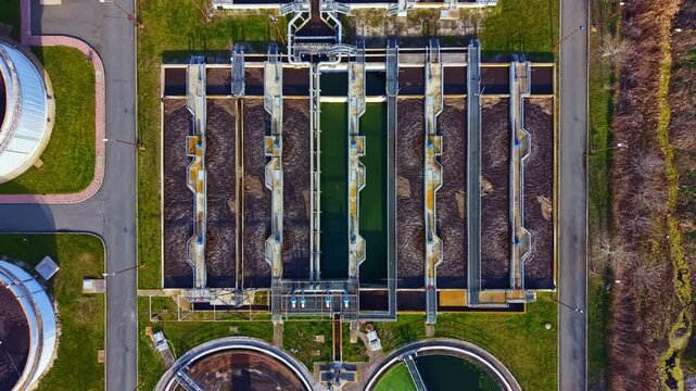 The layout shows multiple sections of a water treatment facility where wastewater is processed. Several large tanks and concrete structures can be seen. Green areas surround the facility.