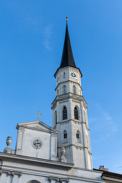 View of a radiant white church crowned with a dark spire pierces the clear blue sky, a serene contrast of color and architectural detail, Vienna, Vienna, Austria.