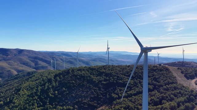 Aerial view of wind turbines halted below cut-in wind speed in mountainous terrain, blades stationary, no rotor torque or power output, illustrating intermittency of wind energy systems