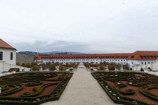 View of formal gardens lead the eye toward a long, red-roofed building under a vast, muted sky, a scene of serene symmetry, Bratislava, Bratislava Region, Slovakia.