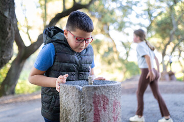 Naklejka premium Boy drinking water from public park fountain