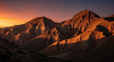 Naklejka premium Majestic mountain peaks bathed in golden sunset light showcasing dramatic natural beauty and rugged terrain