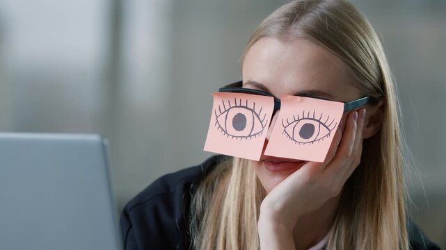 Tired Caucasian business woman pretending working laptop with sticky notes with drawing eyes on glasses businesswoman nap sleepy female girl pretend work in office sleeping falling unmotivated manager