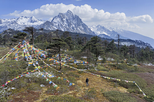 Aerial view of prayer flags fluttering against a backdrop of jagged, snow-capped peaks, Deqing, Yunnan, China.