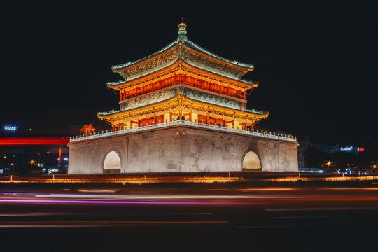 view of the ancient Bell Tower illuminated with vibrant red and gold lights amidst the dark cityscape, Xi'an, China.