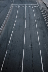 Fototapeta premium A minimalist top-down view of an empty road with crisp white markings and stop lines. The dark asphalt texture and strict geometry of the lines create an aesthetic industrial look.