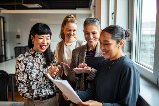 Coworkers celebrating colleague's achievement in modern office