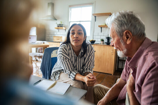 Caregiver consulting with senior man in home kitchen