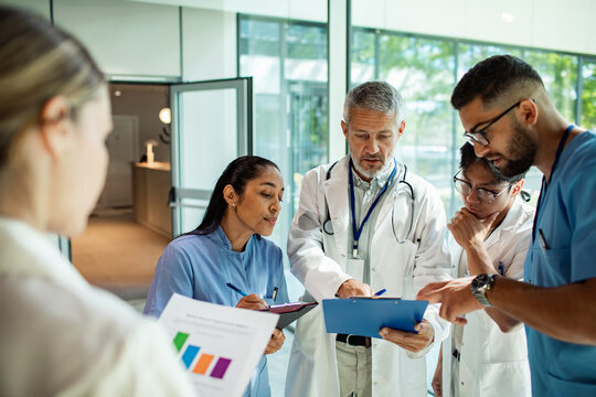 Doctors and nurses reviewing patient charts in hospital corridor