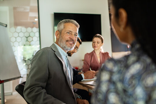 Smiling senior manager leading team meeting in modern office