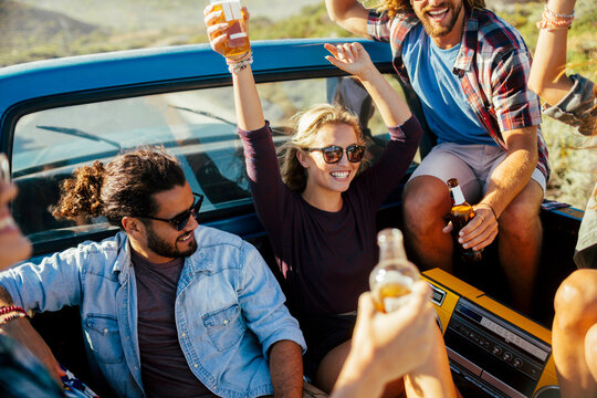 Friends celebrating with drinks in pickup truck outdoors