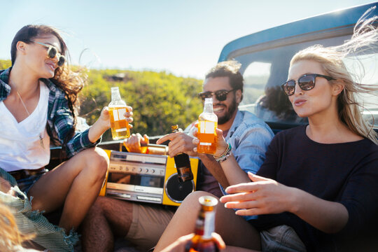 Friends toasting beer in pickup truck outdoors