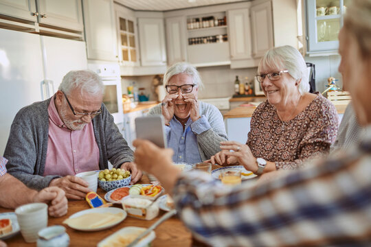 Senior friends laughing over breakfast in a cozy home kitchen
