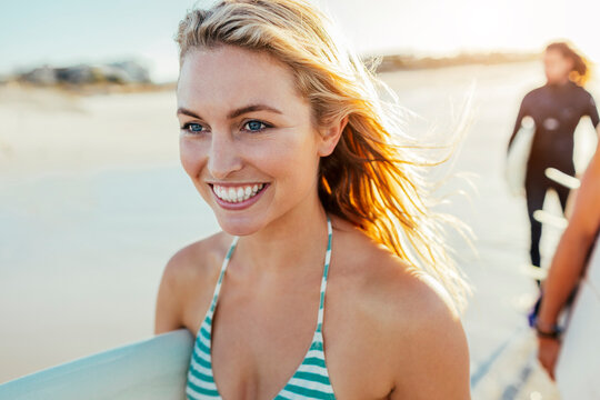 Smiling female surfer with board on sunny beach