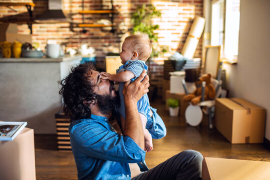 Father lifting baby in new home with moving boxes