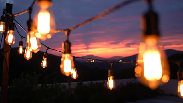 Warm string lights hanging outdoors against a beautiful sunset sky