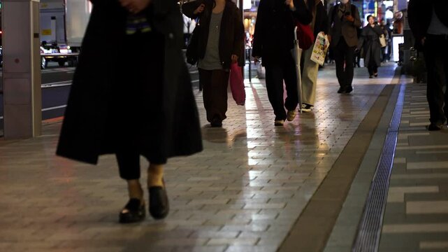 People walking in front of wooden vertical slats wall with warm lighting, urban lifestyle scene captured in real time. Ideal for business, lifestyle and modern city background footage.